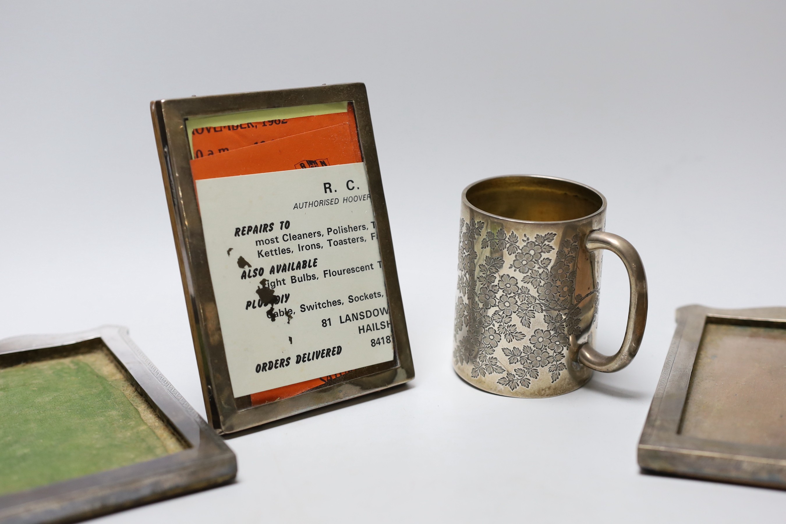 A Victorian engraved silver christening mug, London, 1890, 81mm, a silver napkin ring, a repousse silver dish and three silver mounted photograph frames.